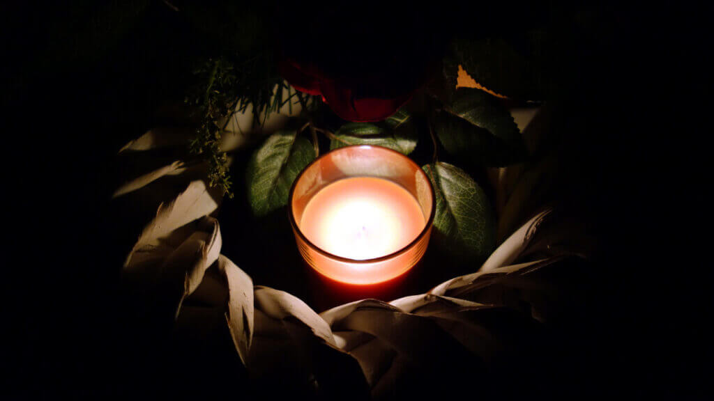 a small lit candle surrounded by darkness