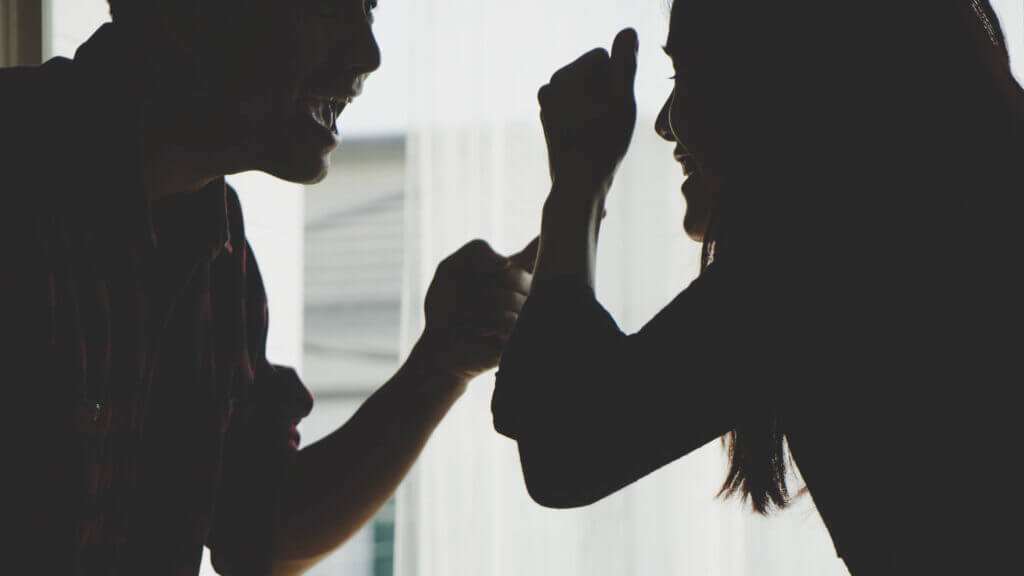 silhouette of a man and woman arguing with raised hands