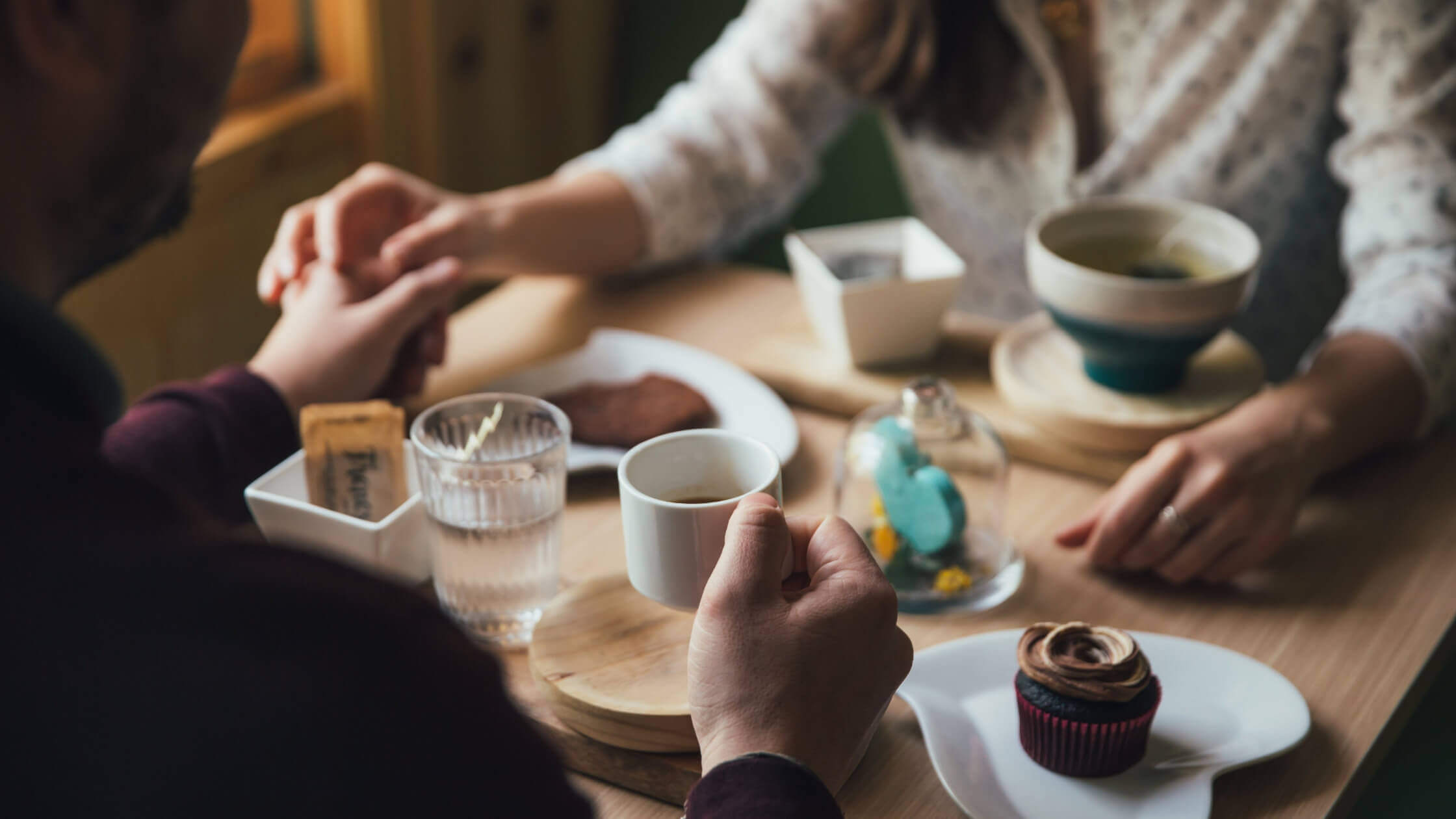 a couple holding hands at a table with dishes of food