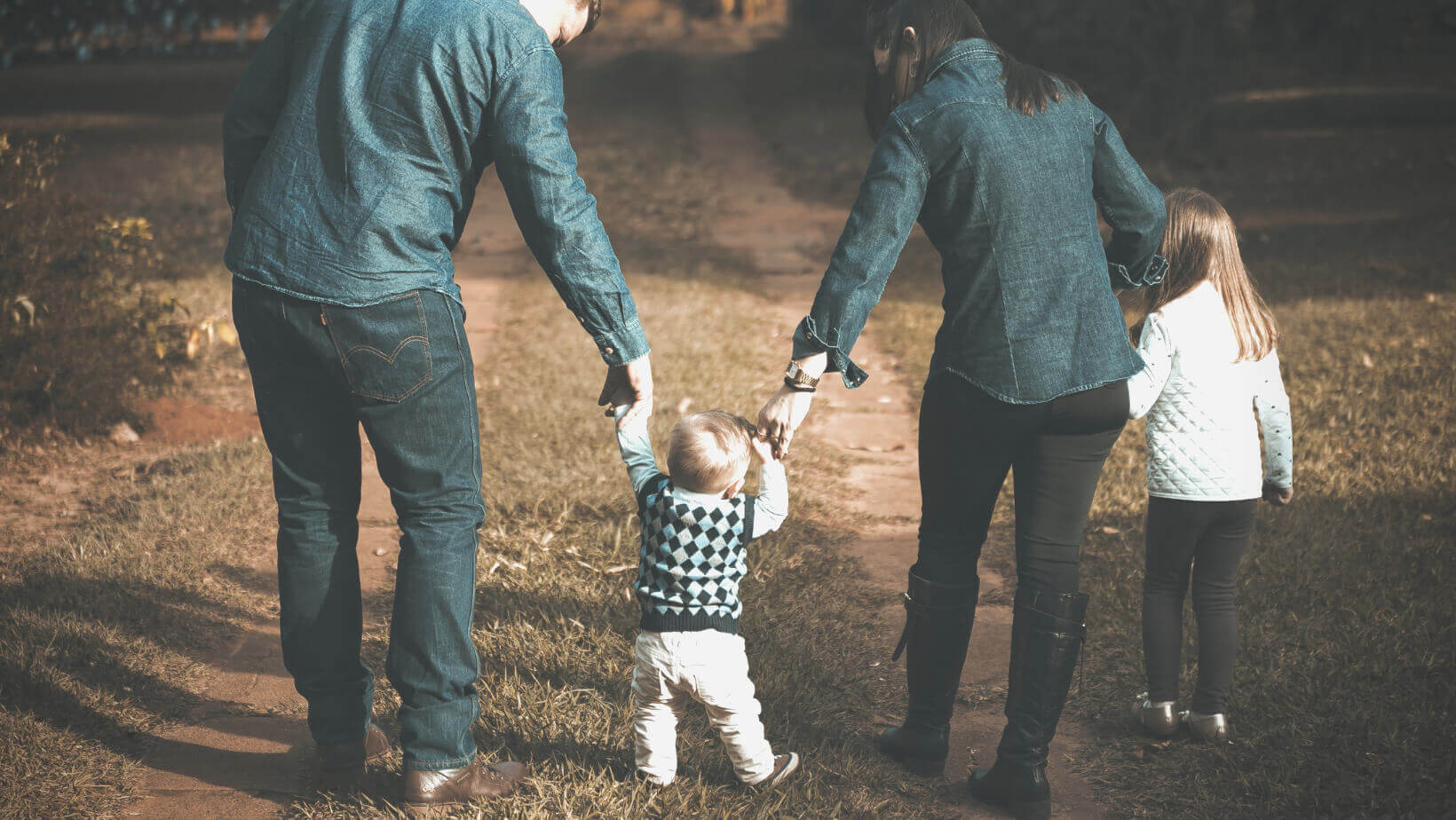 a man and woman each hold the hands of their small child between them