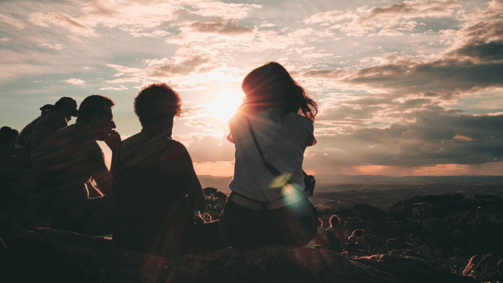 a small group of women and men watch a sunset