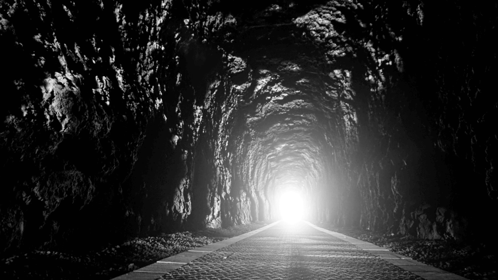 a black and white image of a light at the end of a long tunnel