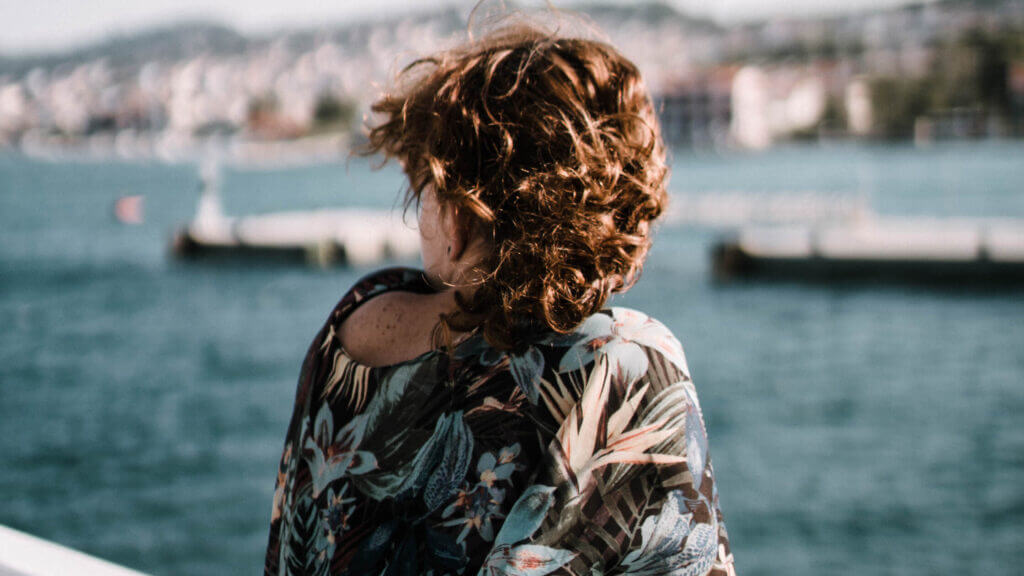 back view of woman looking over her shoulder at water on a dock