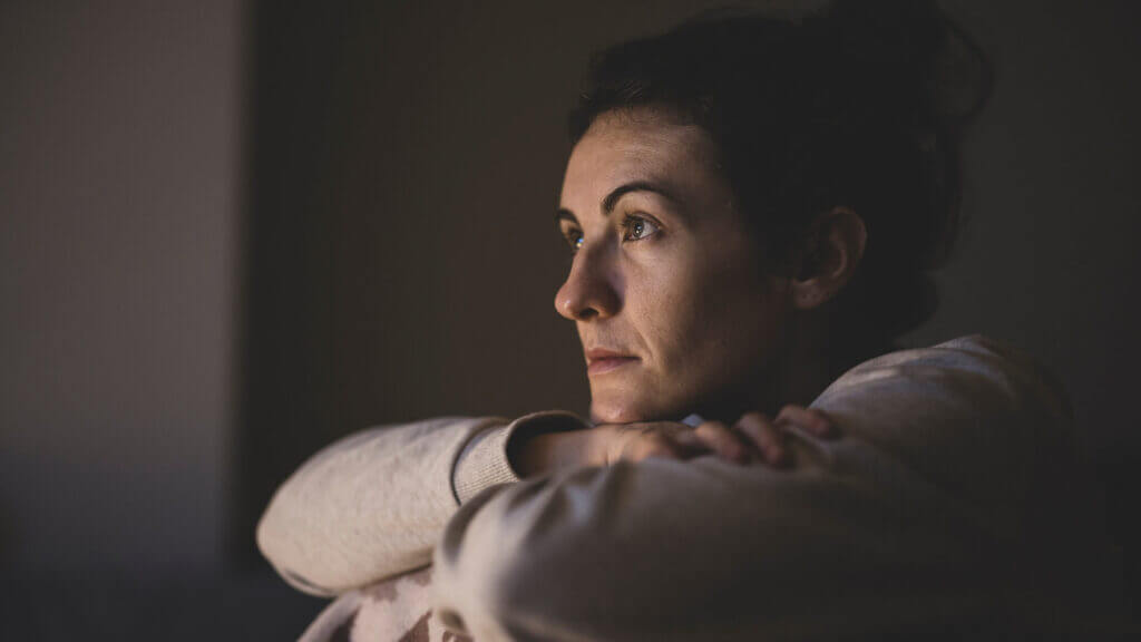 woman with her head on folder arms looking forward without emotion