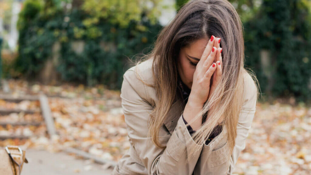 woman praying with her hands held up to her face in despair