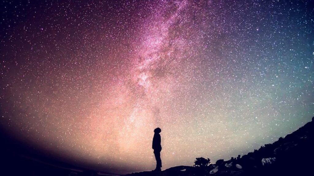 man gazing up at night sky of stars loneliness