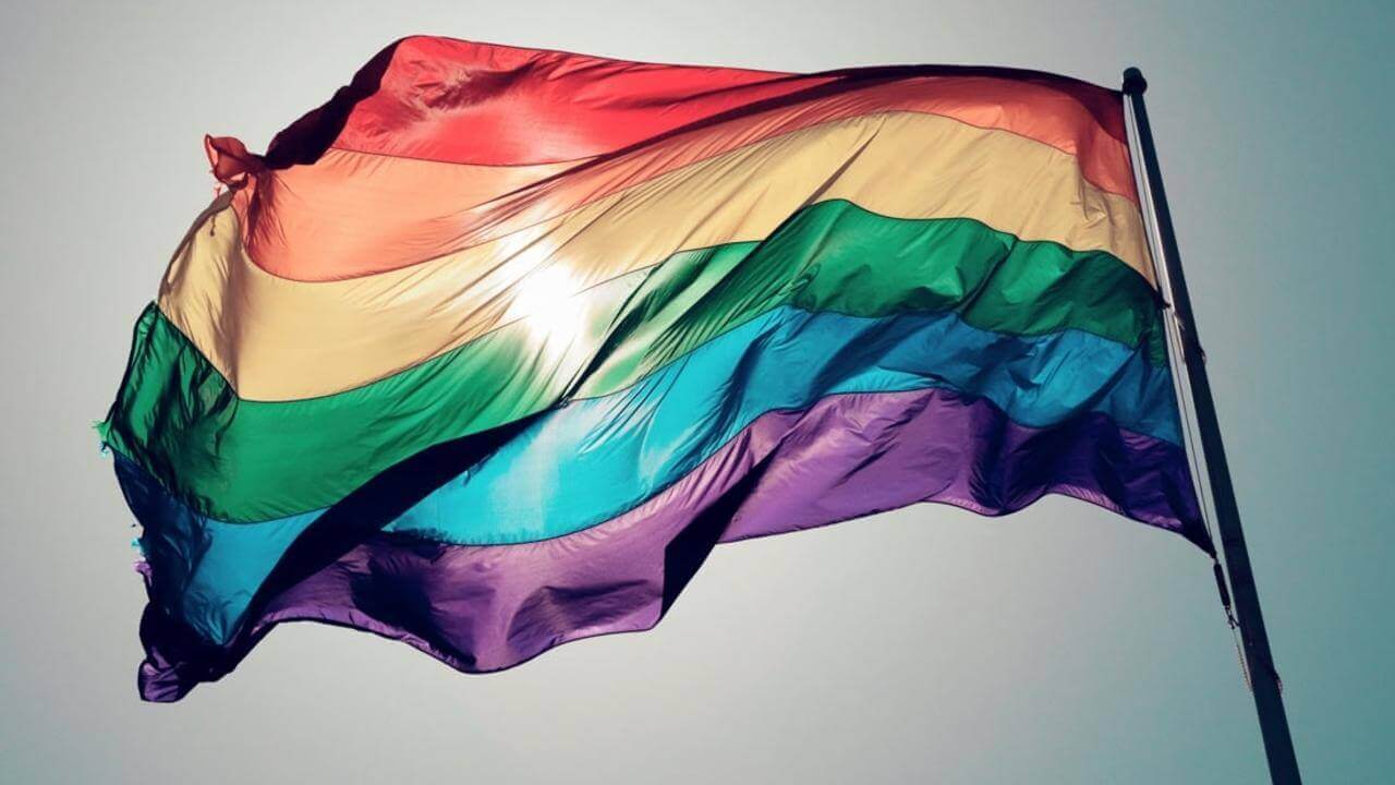 pride flag blows in the wind against the sky same sex attraction
