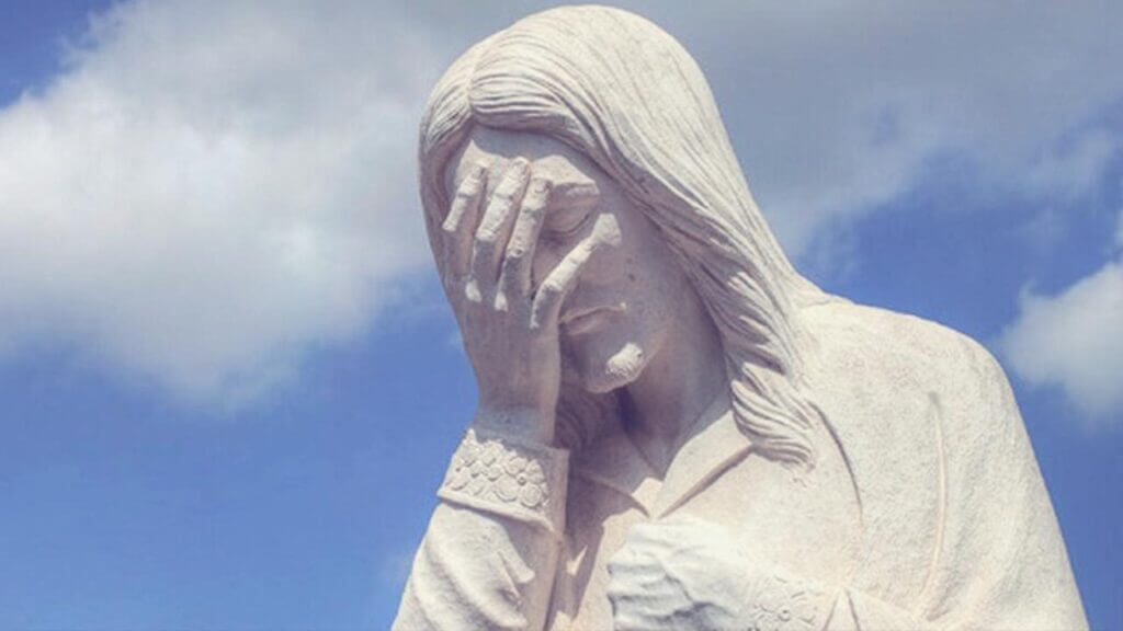 a white statue of Jesus holding his hand up over his face -  bishop scandals