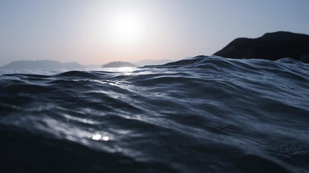 a dark blue wave of water with horizon and bright sky behind it arguing in marriage