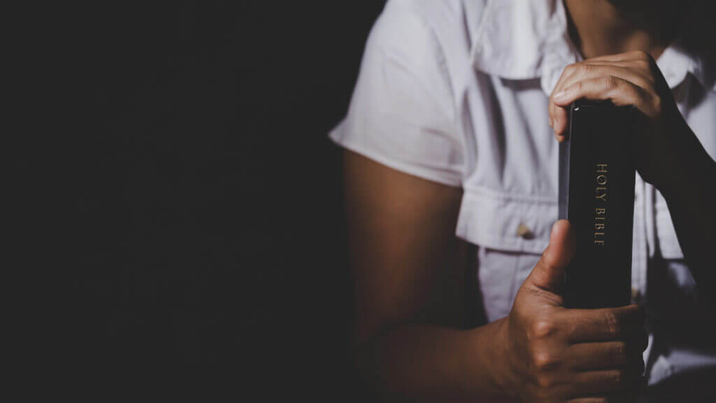 a woman holding a bible between both of her hands, inner spiritualizer