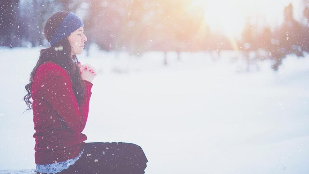 a woman kneels in prayer at a snowy meadow what is catholic mindfulness